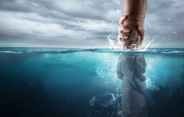 A hand reaches down into the water and saves someone drowning.